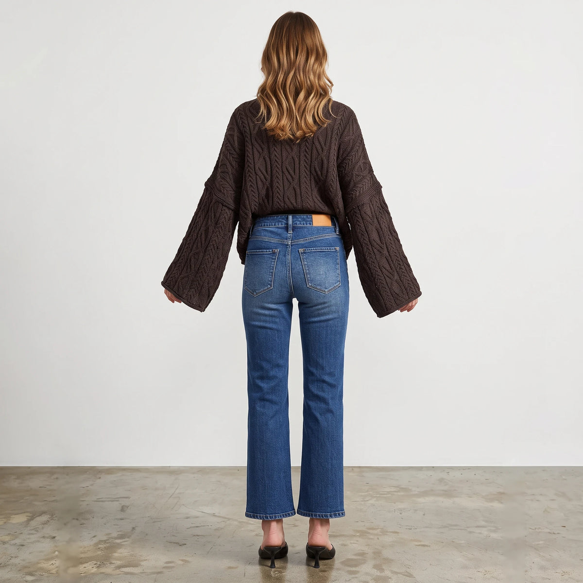 Back view of a woman wearing an Apricot Lane Duluth oversized dark brown cable knit sweater with wide sleeves.