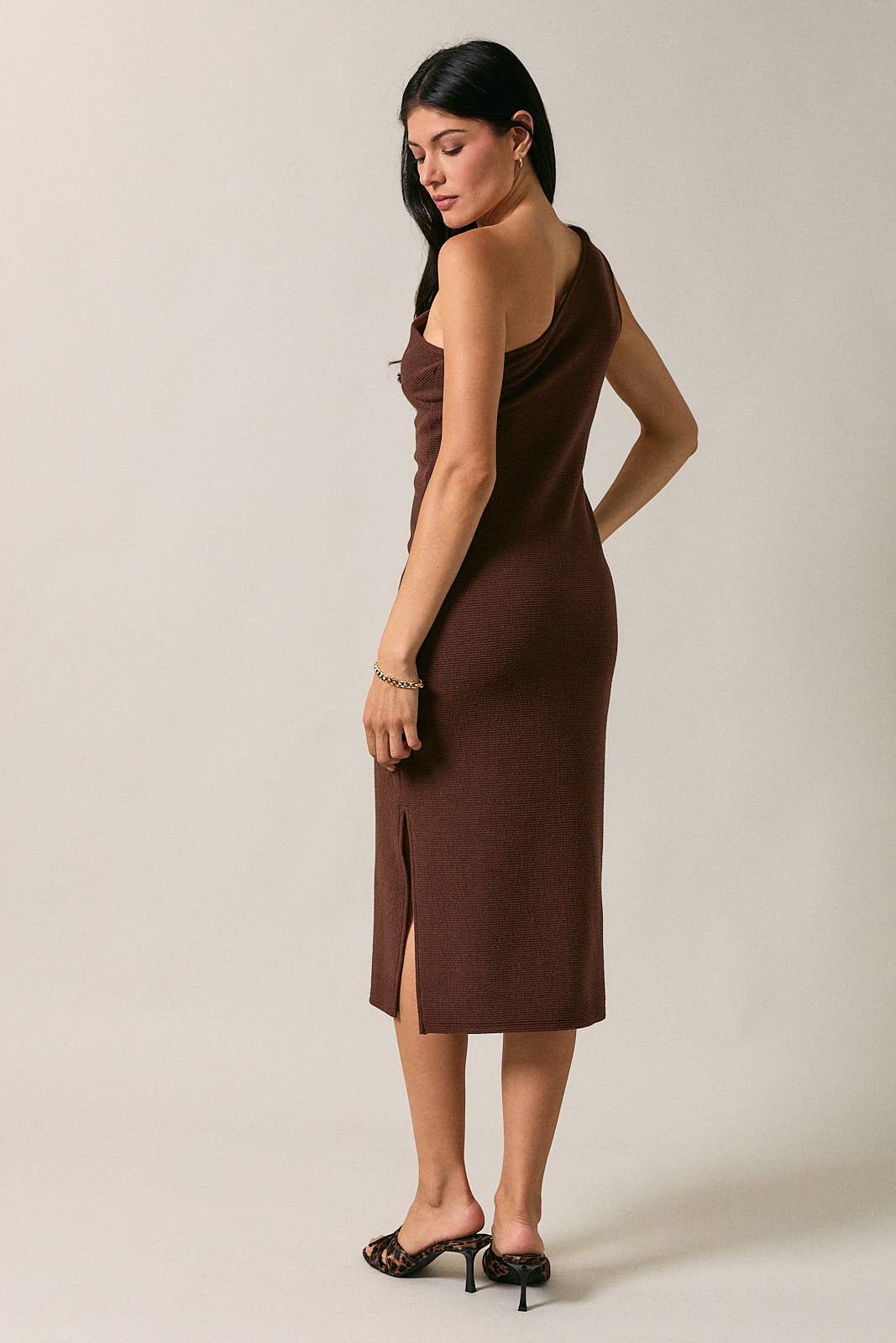 Model wearing Apricot Lane Duluth Gabrielle one-shoulder brown midi dress with side slit and cutout detail