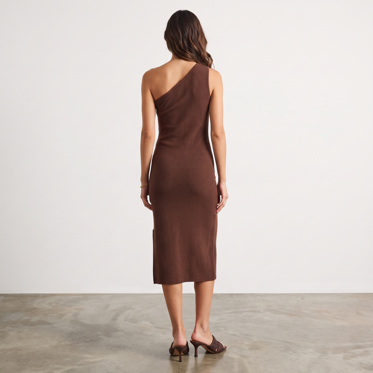 Back view of a woman wearing the Apricot Lane Duluth brown one-shoulder midi dress with a sleek fitted silhouette.
