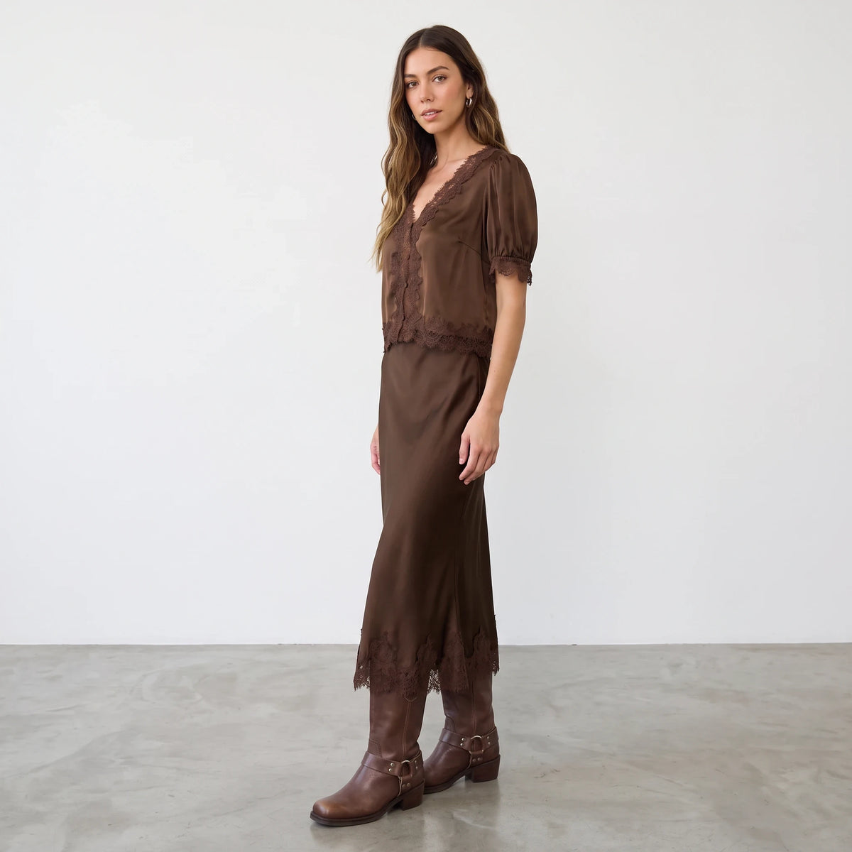 Model wearing Apricot Lane Duluth brown satin blouse with lace trim and matching midi skirt with leather boots