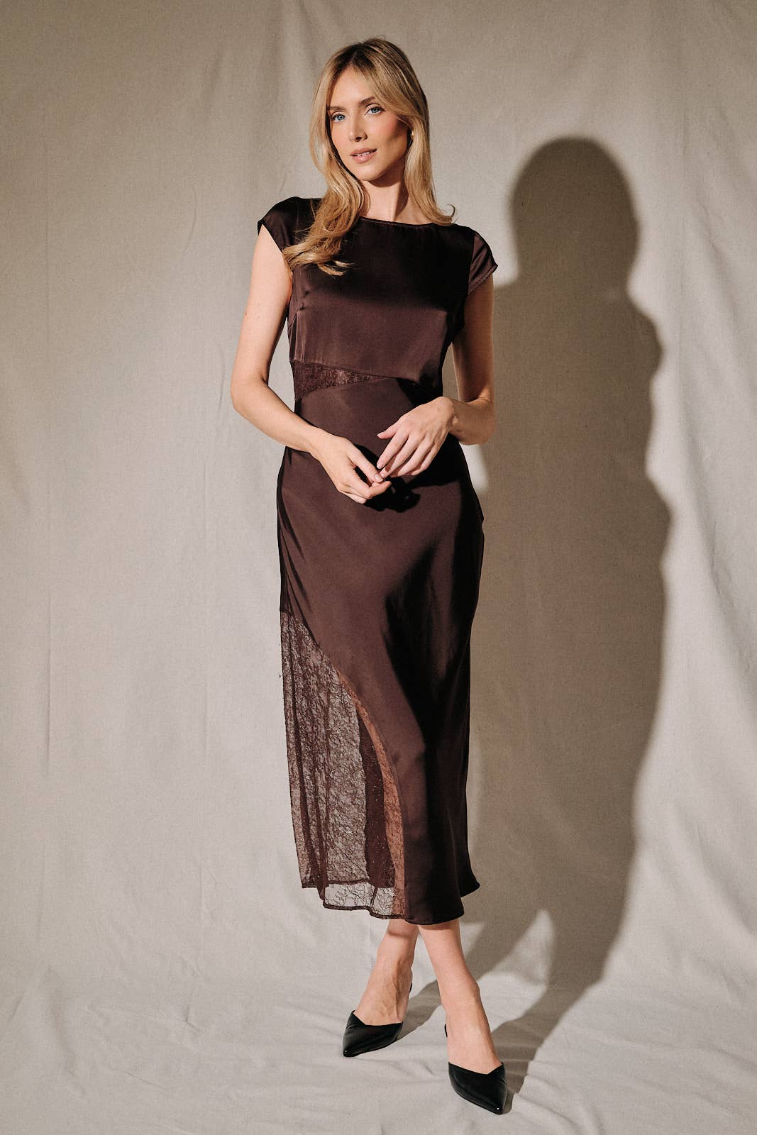 Model wearing Apricot Lane Duluth brown satin midi dress with cap sleeves and sheer lace waist and skirt inserts