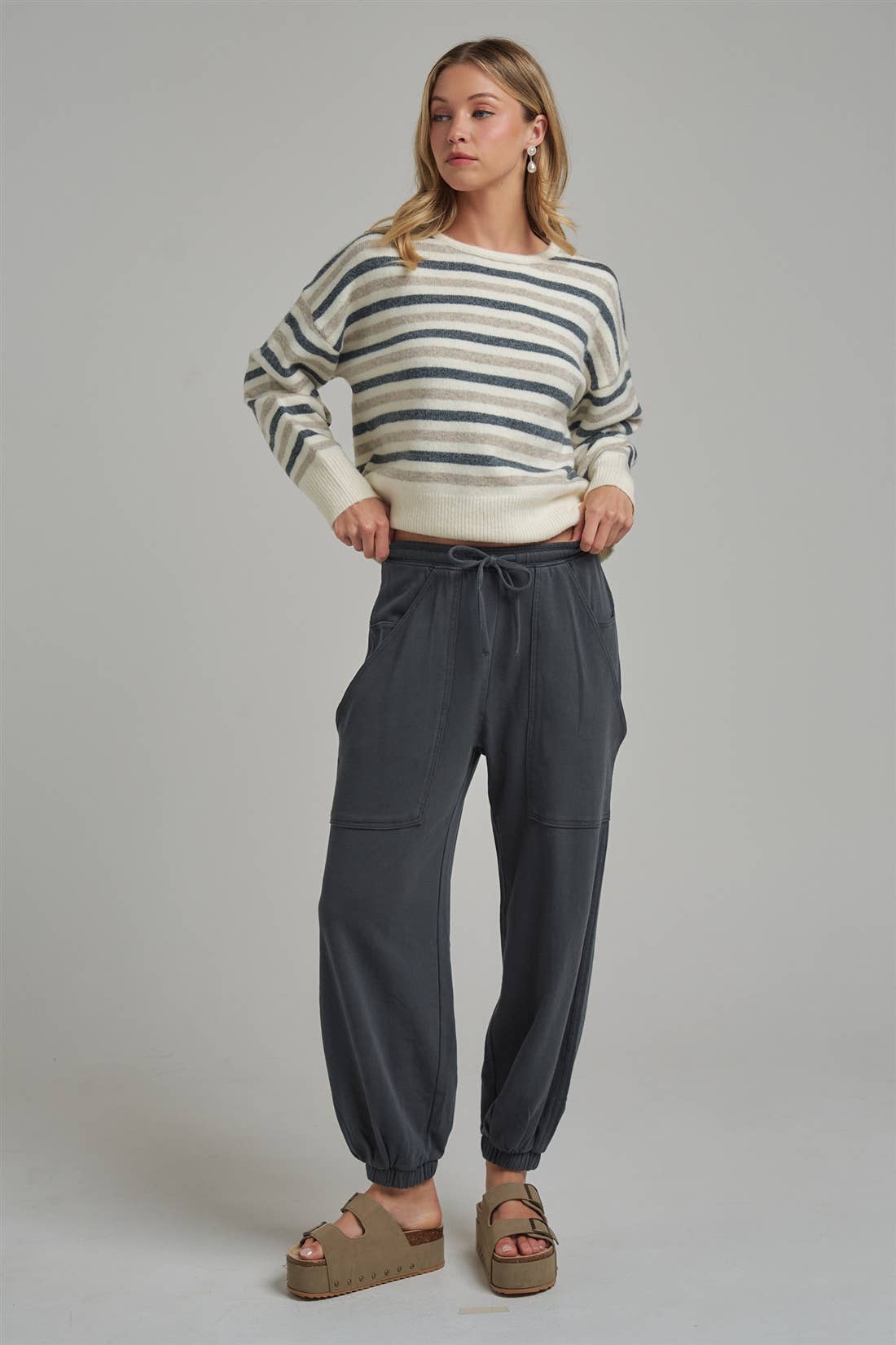 Model wearing Apricot Lane Duluth Dakota cargo joggers in charcoal with a striped sweater and platform sandals