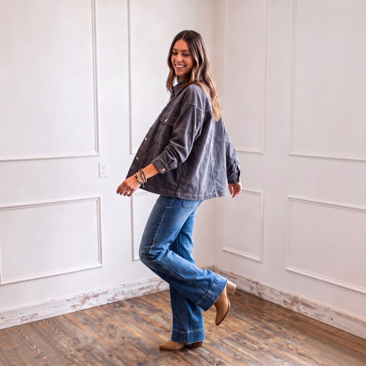 Woman wearing an Apricot Lane Duluth charcoal grey corduroy shacket with blue jeans and tan boots in a bright room.