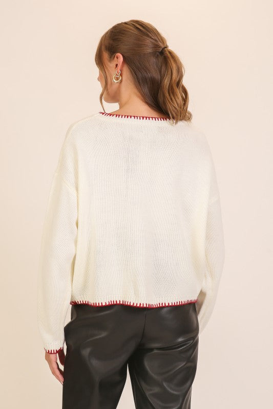 Back view of Apricot Lane Duluth cream knit sweater with red contrast stitching on the neckline, cuffs, and hem.