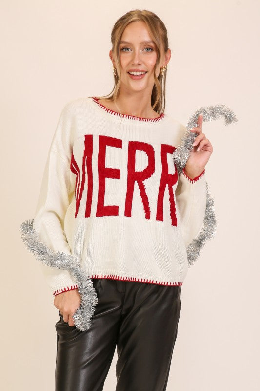 Model wearing an Apricot Lane Duluth cream knit sweater with a red MERRY graphic and contrast red trim