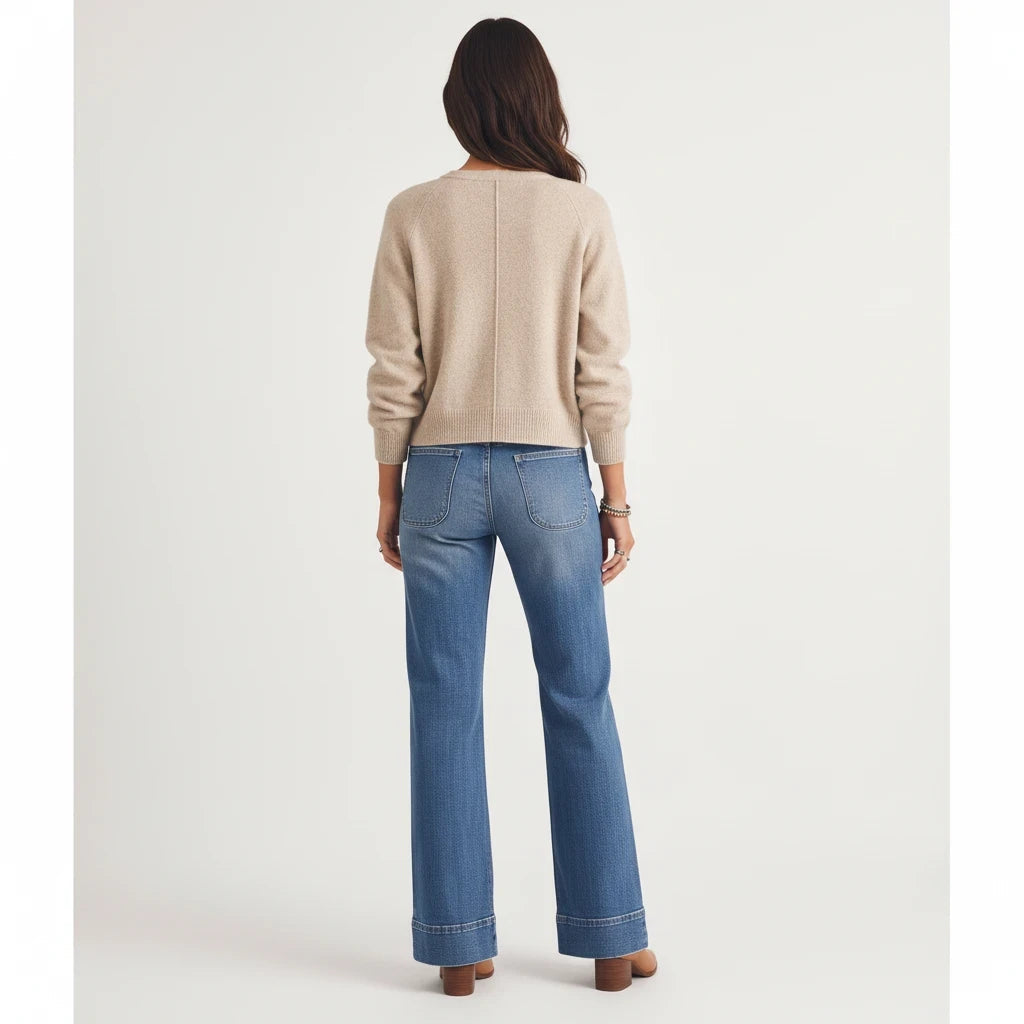 Back view of a woman wearing an Apricot Lane Duluth beige knit cardigan with long sleeves and blue denim jeans.