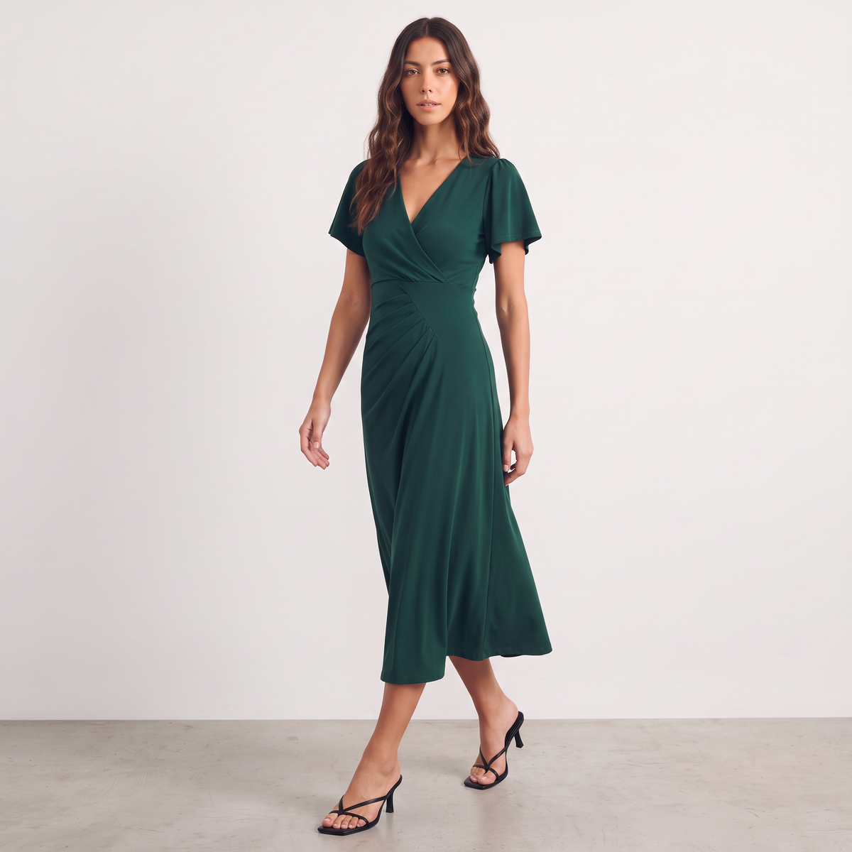 Model wearing an Apricot Lane Duluth dark green midi dress with a surplice V-neck, flutter sleeves, and pleating.