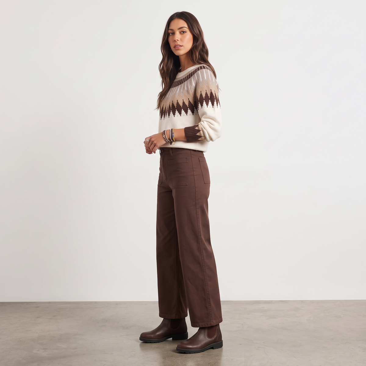 Model wearing Apricot Lane Duluth Brynn Fair Isle yoke sweater with geometric patterns, brown trousers, and boots.