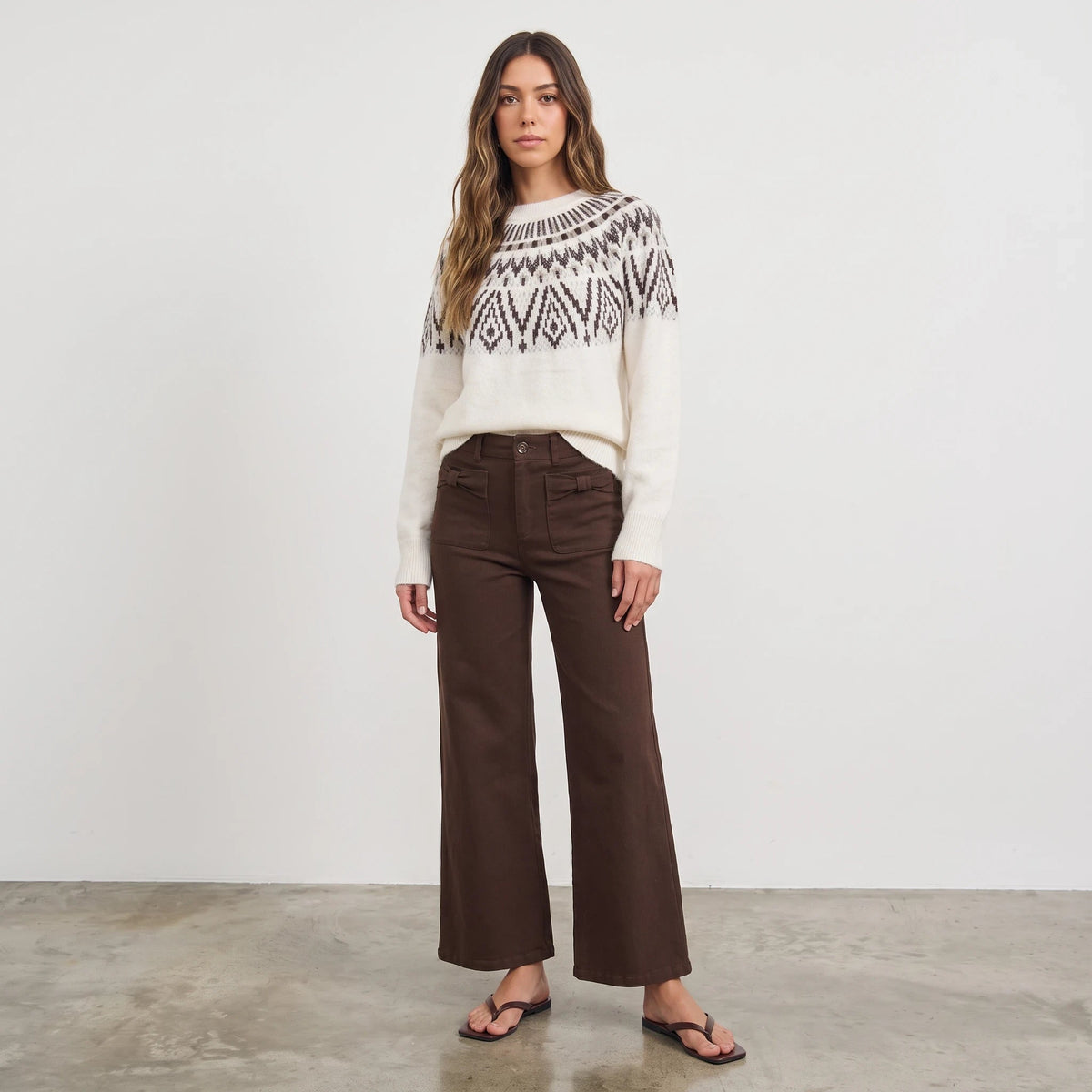 Model wearing Apricot Lane Duluth Margot Fair Isle sweater with geometric yoke and brown wide-leg trousers