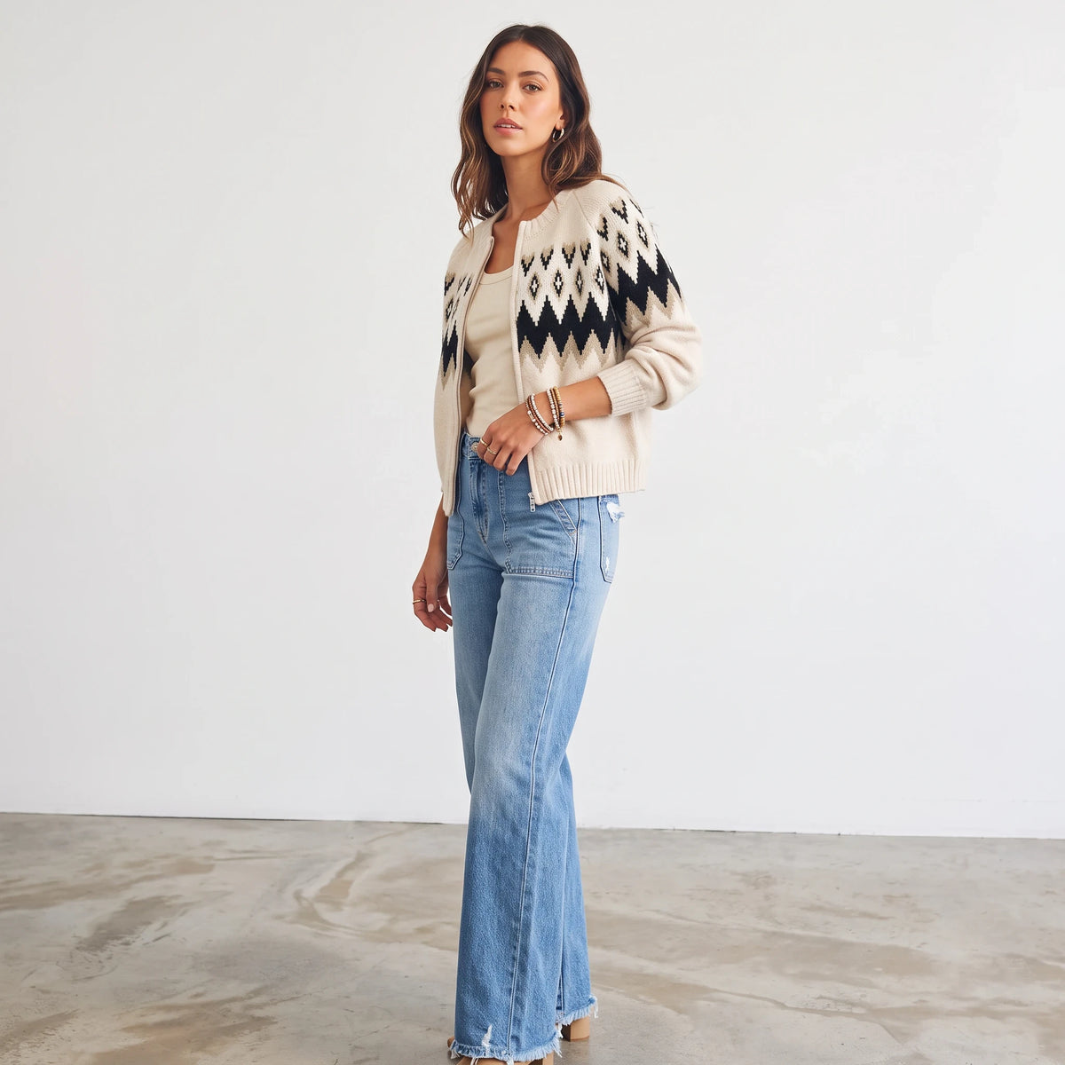 Model wearing an Apricot Lane Duluth black and cream Fair Isle zip-front knit cardigan with blue denim jeans
