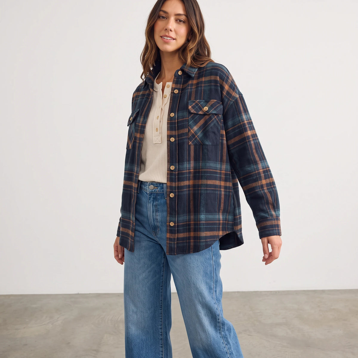 Model wearing an Apricot Lane Duluth Fallon brushed flannel plaid jacket with chest pockets over a cream henley top.