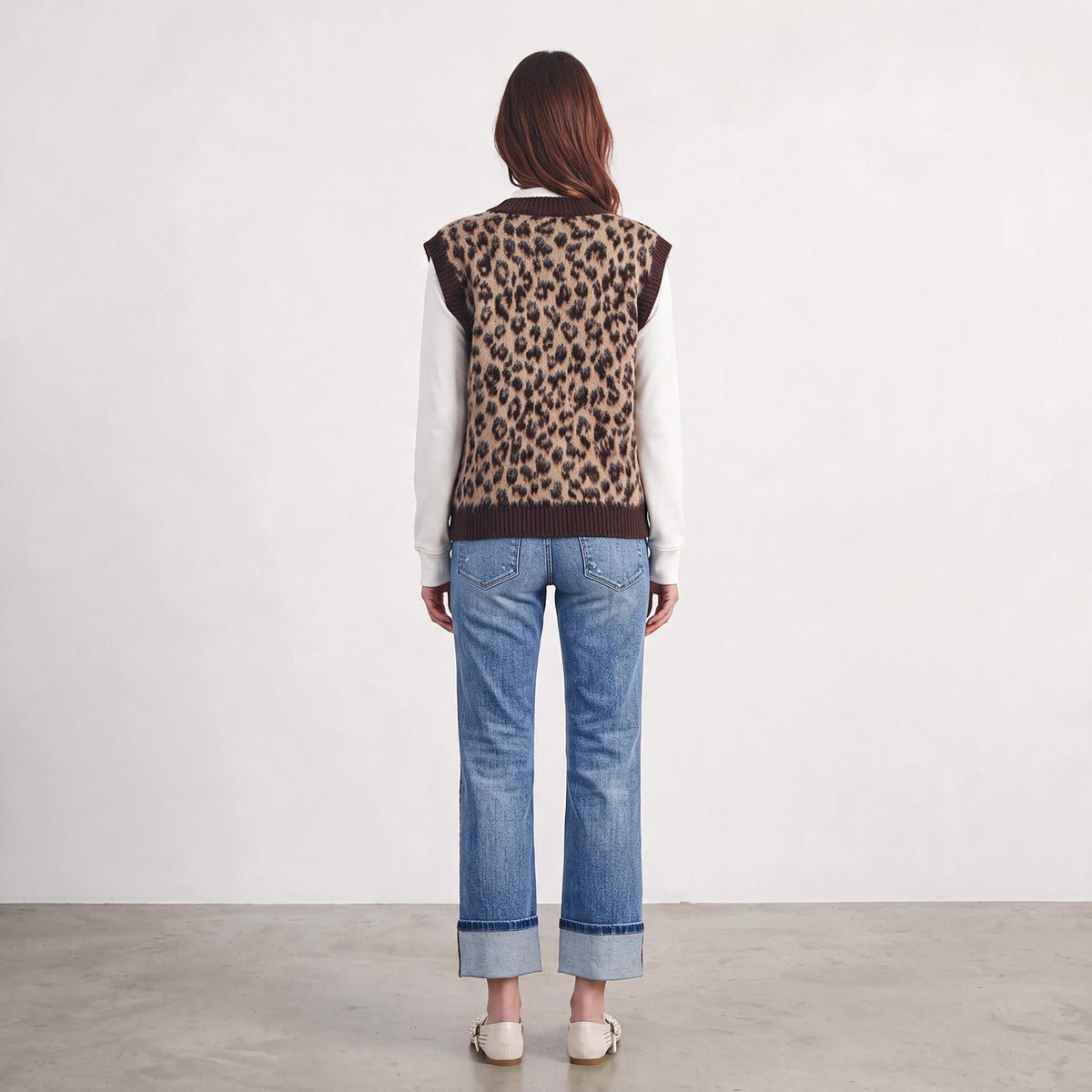 Apricot Lane Duluth leopard print fuzzy sweater vest worn over a white long-sleeve shirt and blue cuffed jeans