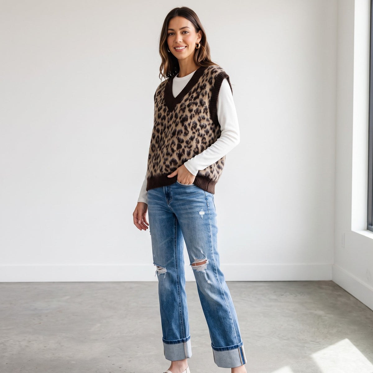 Model wearing Apricot Lane Duluth leopard print fuzzy sweater vest over a white long-sleeve shirt and distressed jeans