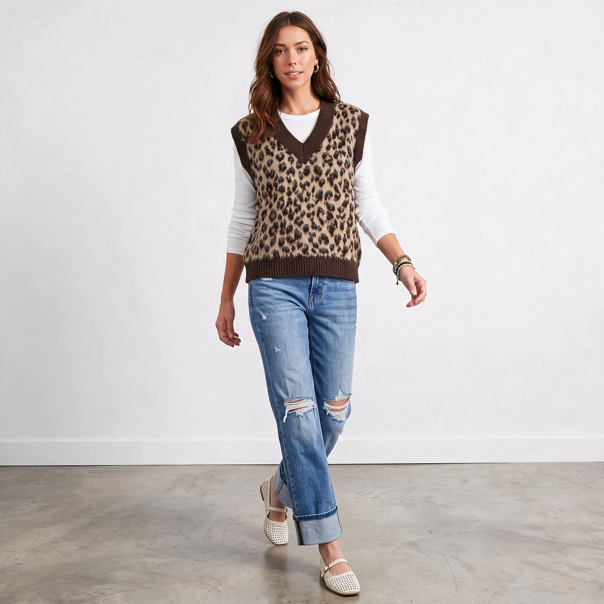 Model wearing Apricot Lane Duluth leopard print fuzzy sweater vest over a white long-sleeve top and distressed jeans