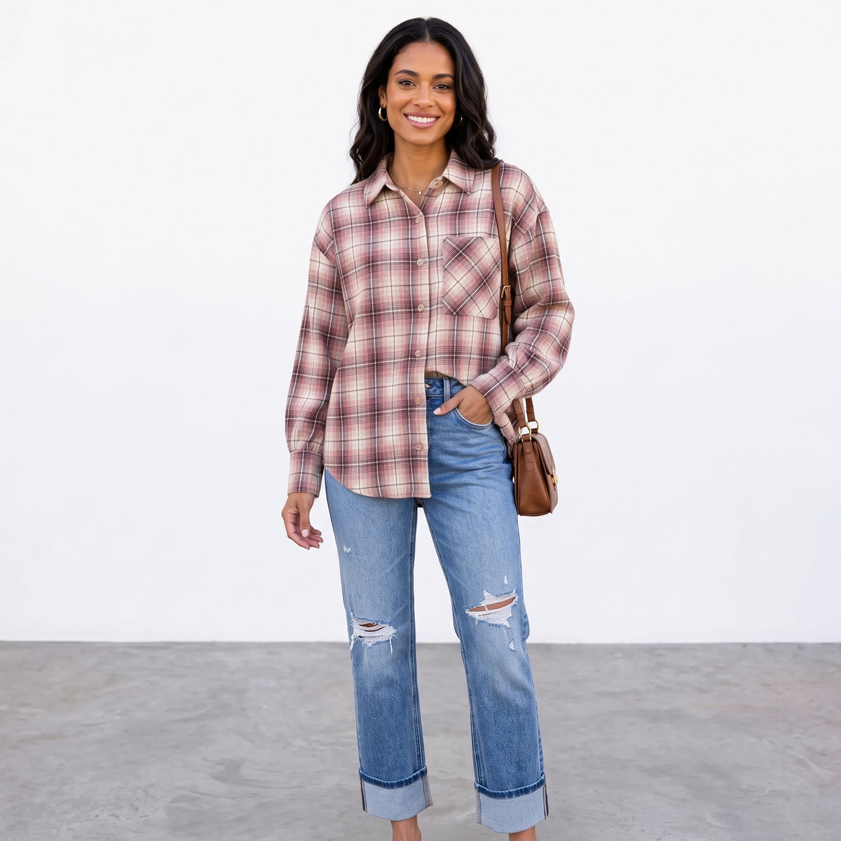 Model wearing Apricot Lane Duluth Maren plaid button-down shirt with blue distressed jeans and a brown shoulder bag.