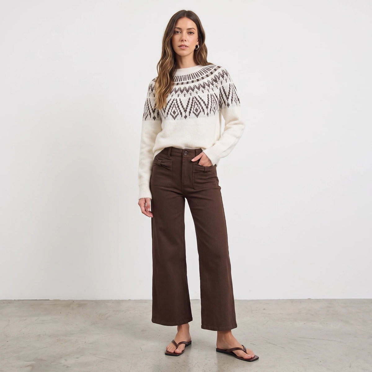 Model wearing Apricot Lane Duluth Margot Fair Isle wool-blend sweater with geometric yoke and brown wide-leg pants.