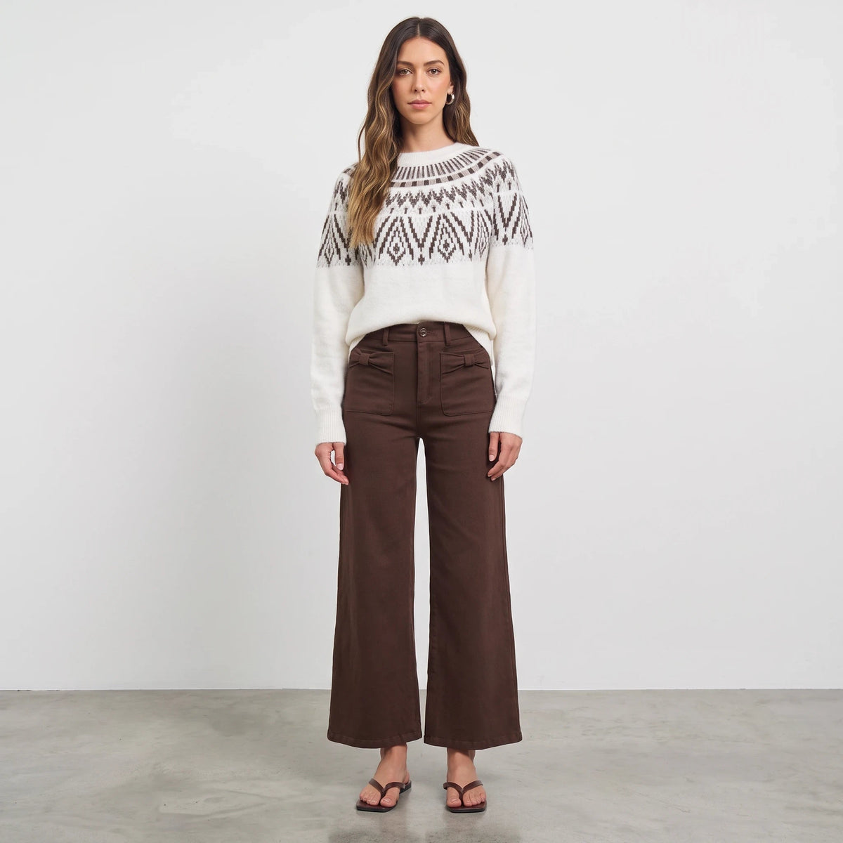 Model wearing an Apricot Lane Duluth Margot Fair Isle sweater with a geometric yoke and brown wide-leg trousers.
