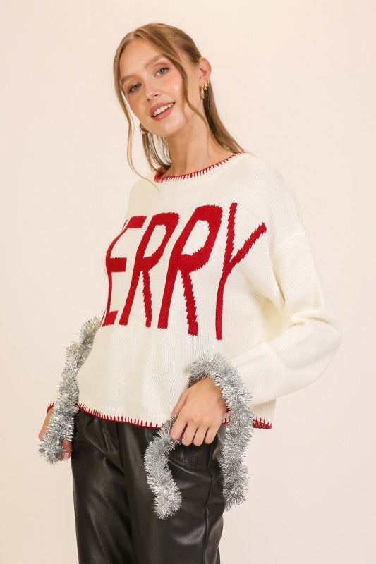 Apricot Lane Duluth cream knit sweater with red MERRY graphic, red trim, and silver tinsel accents on a model.