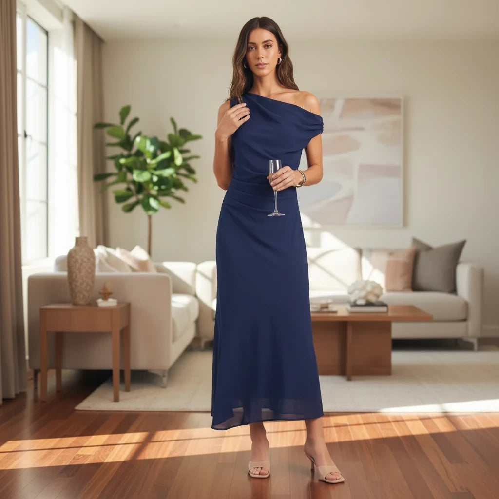 Model wearing Apricot Lane Duluth navy one-shoulder midi dress in crepe fabric with draped back in a bright living room