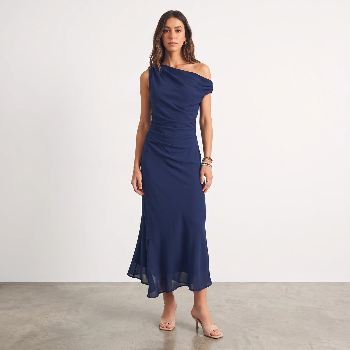Model wearing Apricot Lane Duluth navy one-shoulder midi dress in soft crepe with a body-skimming silhouette.