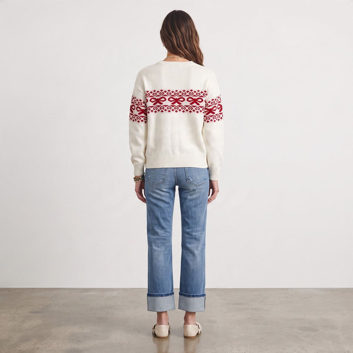 Apricot Lane Duluth Noelle sweater with red bow and heart Fair Isle pattern on cream knit, worn with blue jeans.