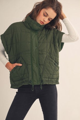 Apricot Lane Duluth olive green quilted puffer pullover vest with a high neck and side pockets worn over a white top
