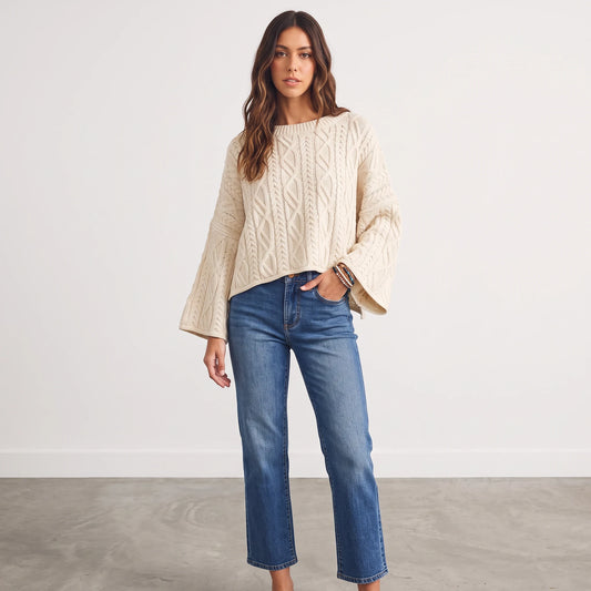 Model wearing Apricot Lane Duluth oversized cream cable-knit sweater with flared sleeves and blue straight-leg jeans.