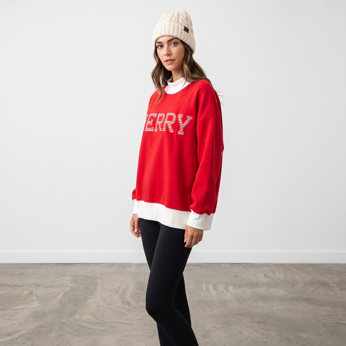 Model wearing Apricot Lane Duluth red oversized mock neck Christmas top with Merry graphic and white ribbed trim