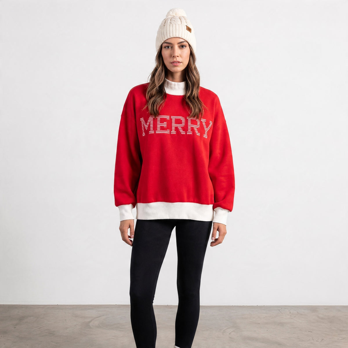 Apricot Lane Duluth red oversized mock neck Christmas top with Merry graphic, worn by a model in a cream beanie