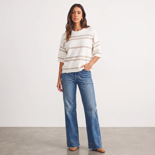 Apricot Lane Duluth model wearing a cream and tan striped short-sleeve knit sweater with wide-leg blue jeans