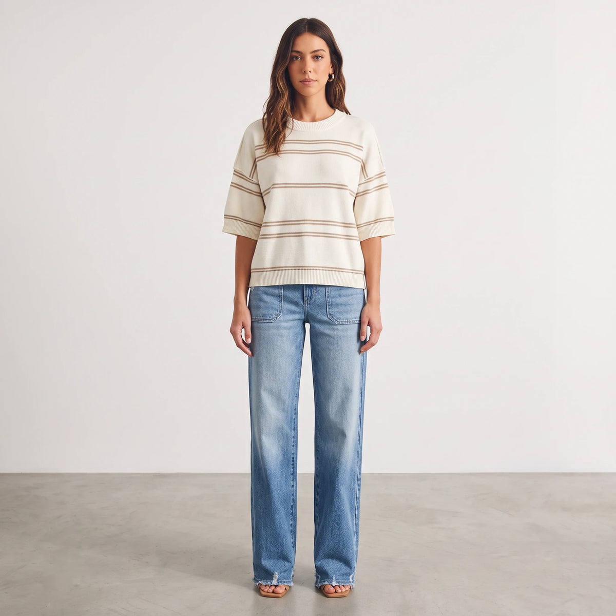 Apricot Lane Duluth model wearing a cream and tan striped short sleeve knit sweater with blue wide-leg denim jeans.