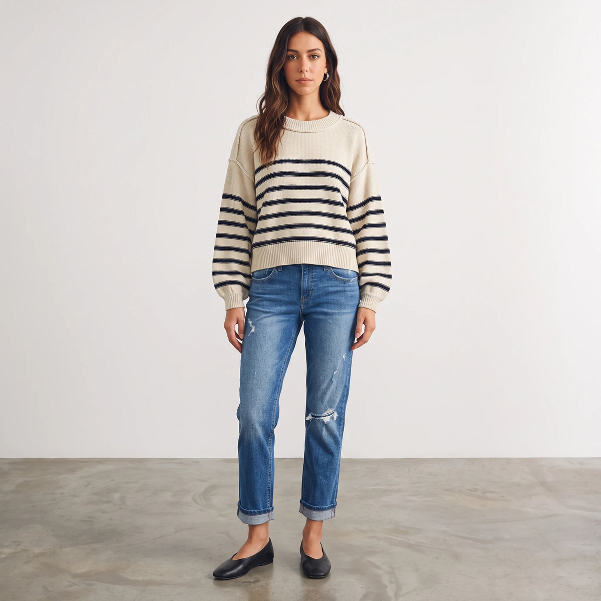 Model wearing an Apricot Lane Duluth cream and navy striped cotton-blend pullover sweater with blue distressed jeans.