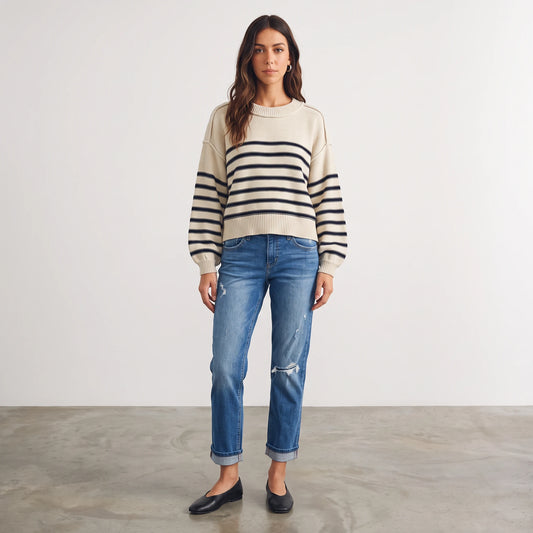 Model wearing an Apricot Lane Duluth cream and navy striped cotton-blend pullover sweater with blue distressed jeans.