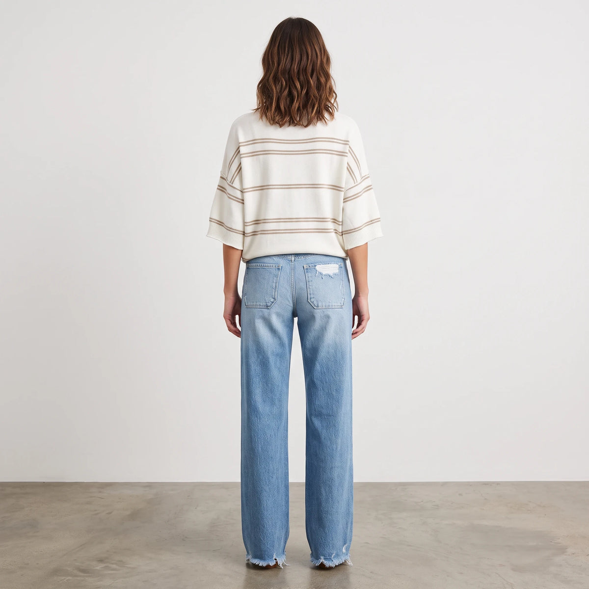 Back view of a woman wearing the Apricot Lane Duluth Sutton striped knit sweater with short sleeves and blue jeans.