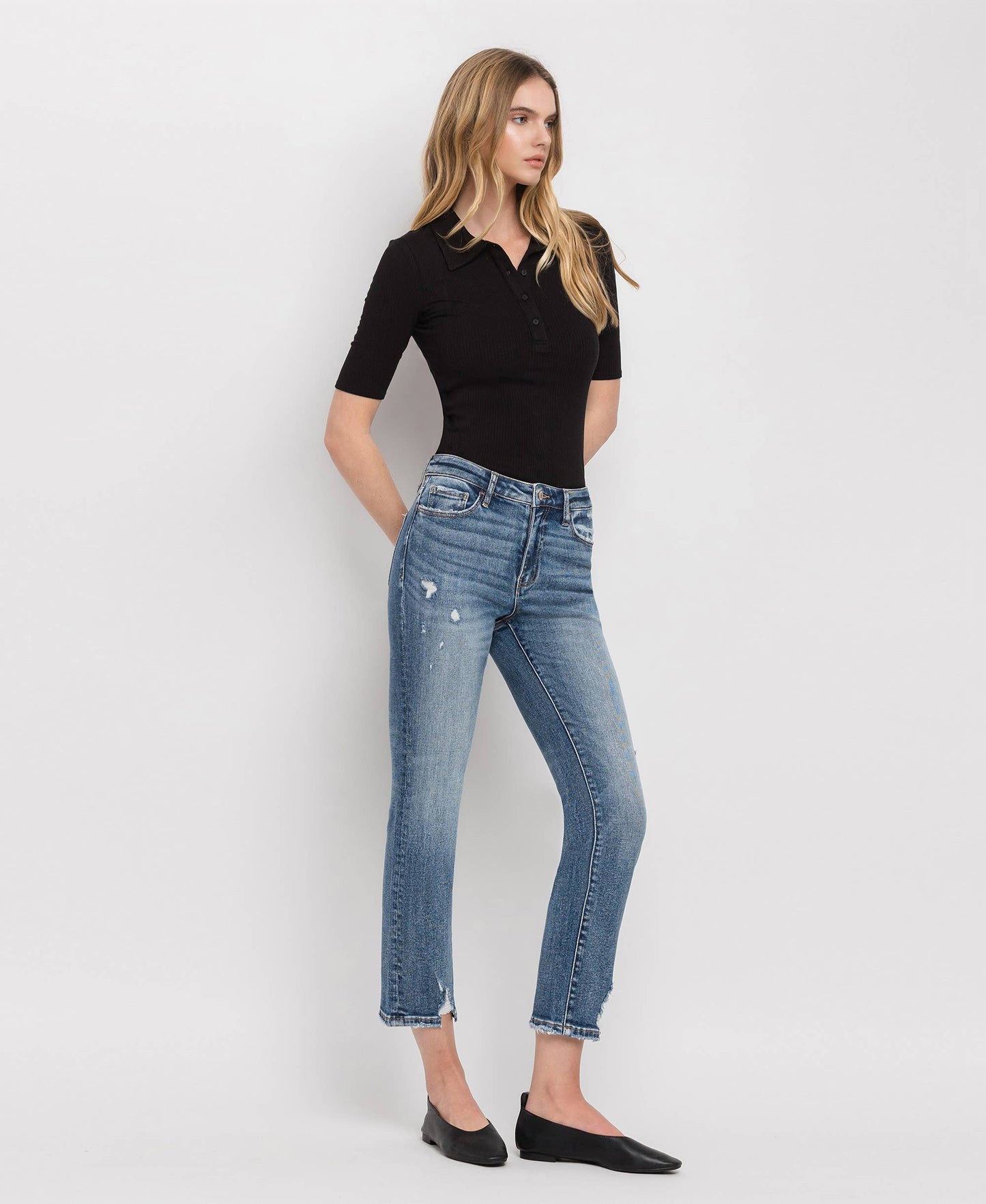 Woman wearing a black top and blue jeans on a white background