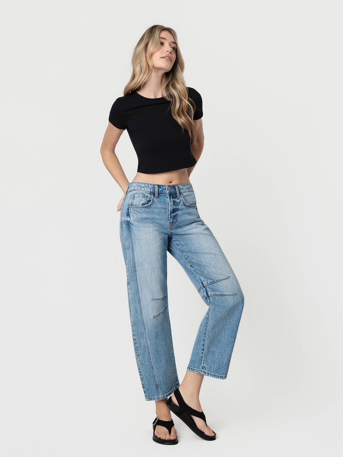 Woman wearing a black crop top and blue jeans on a white background