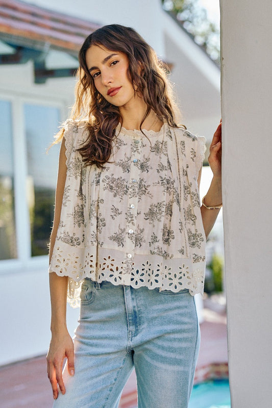 Woman wearing a floral blouse and light blue jeans standing outdoors.
