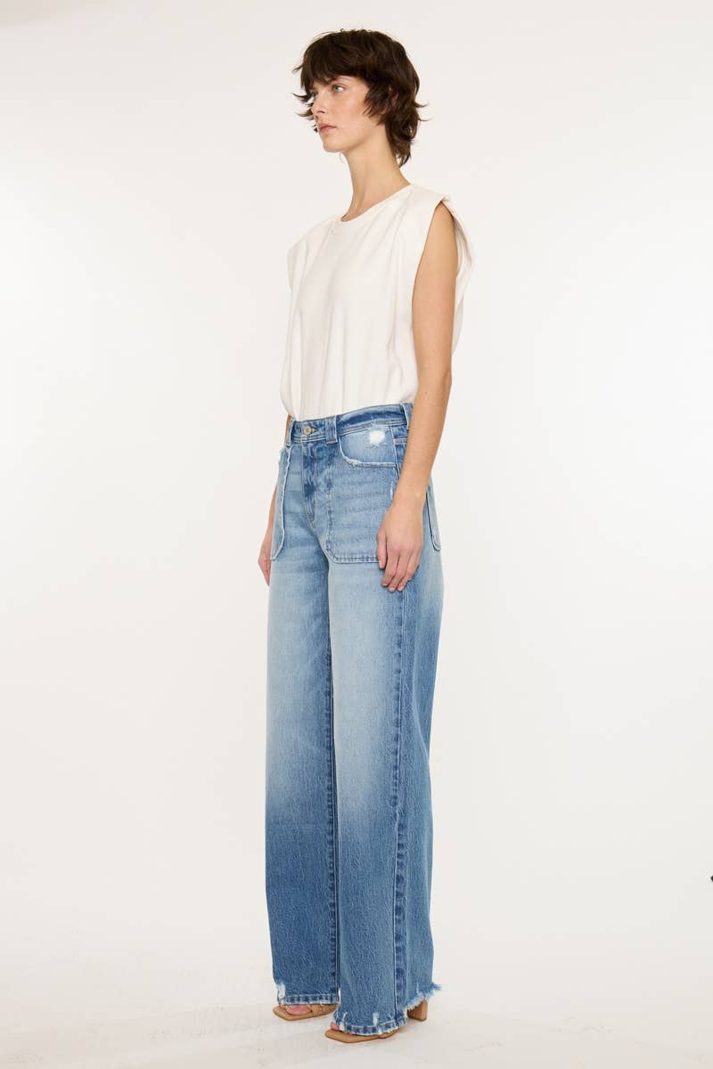 Woman wearing a white sleeveless top and blue jeans on a white background