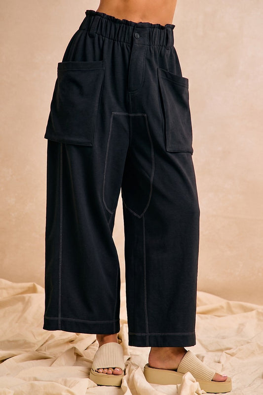 Black wide-leg pants worn by a person on a beige background