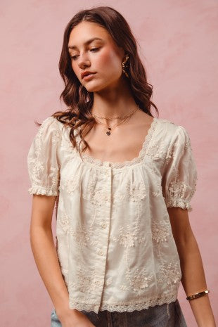 Woman wearing a white lace blouse against a pink background