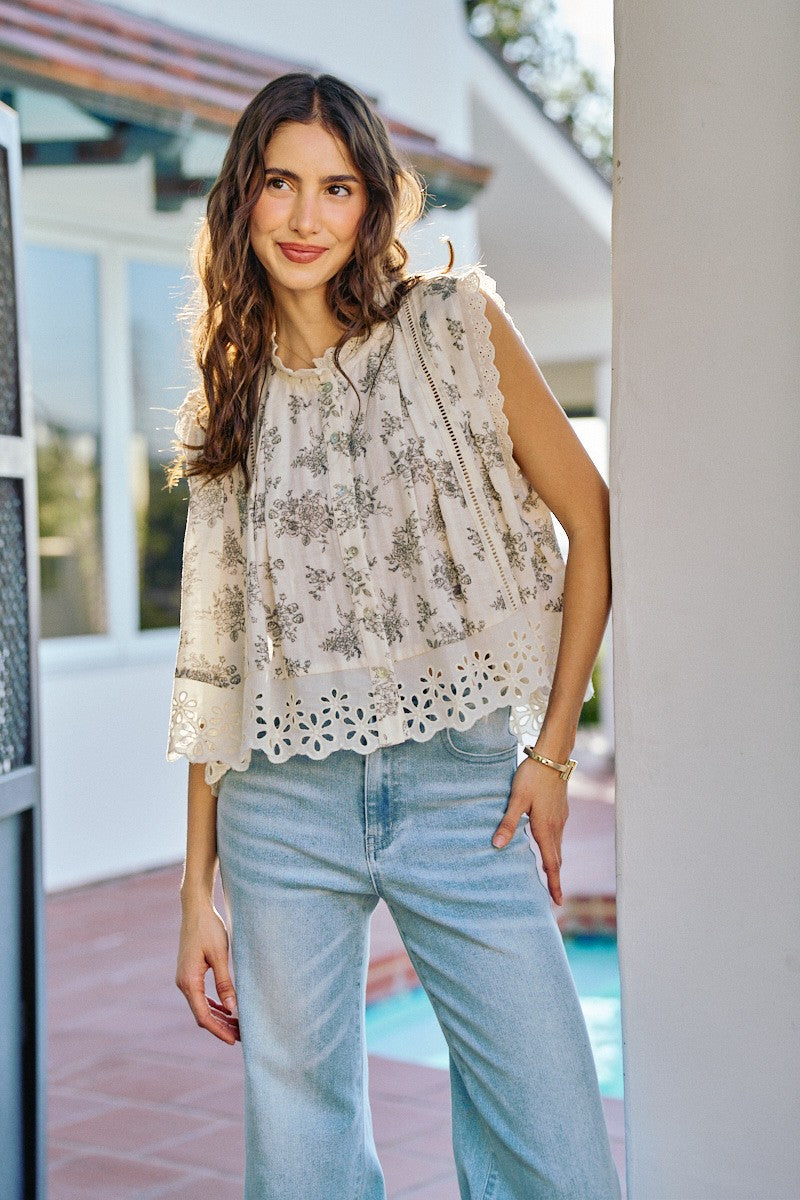 Woman wearing a floral blouse and light blue jeans standing outdoors.