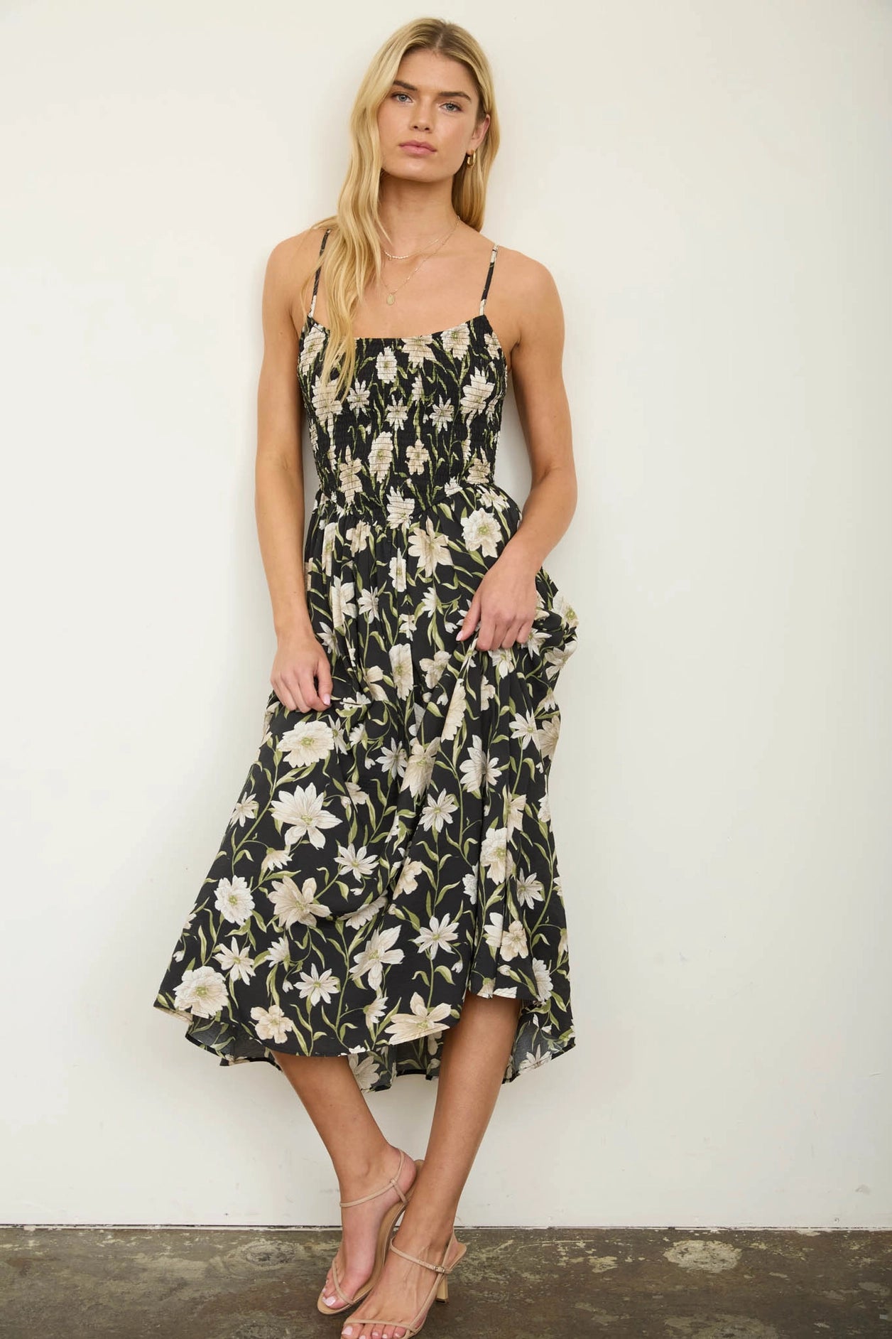 women in black floral dress against white wall