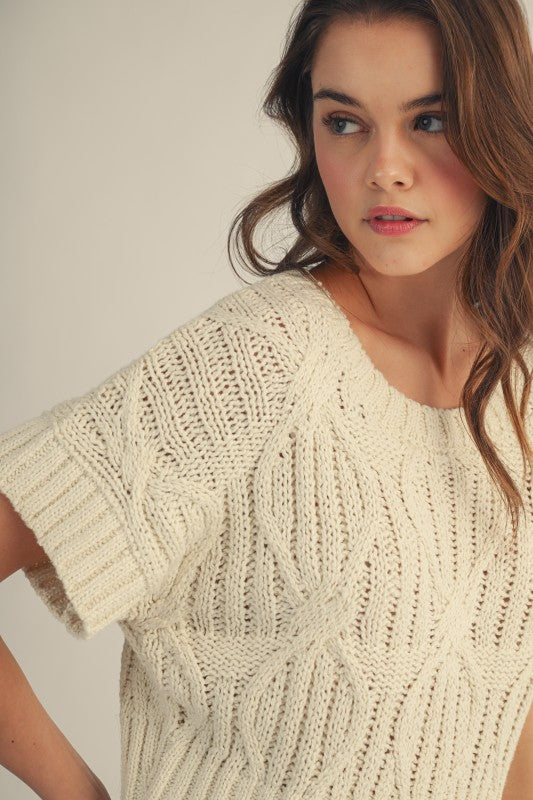 Woman wearing a beige knitted sweater against a plain background