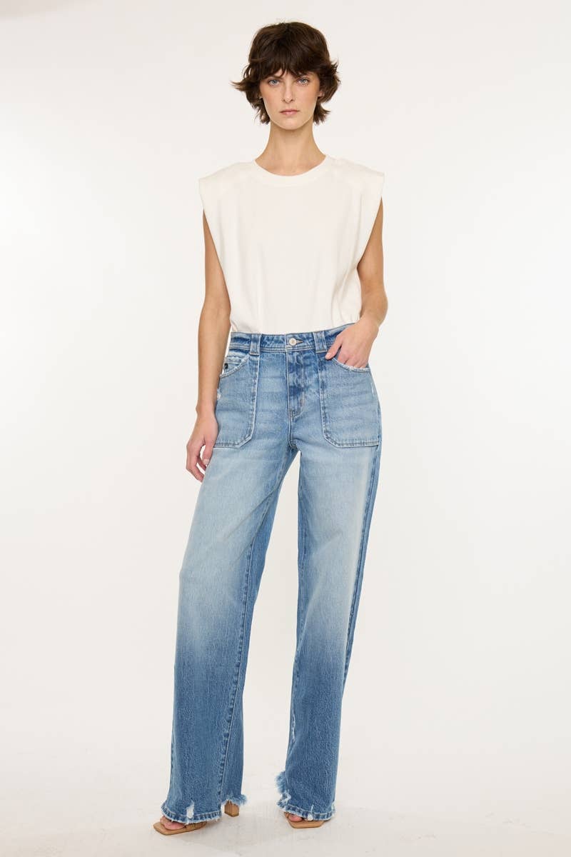 Woman wearing light blue jeans and a white top on a white background