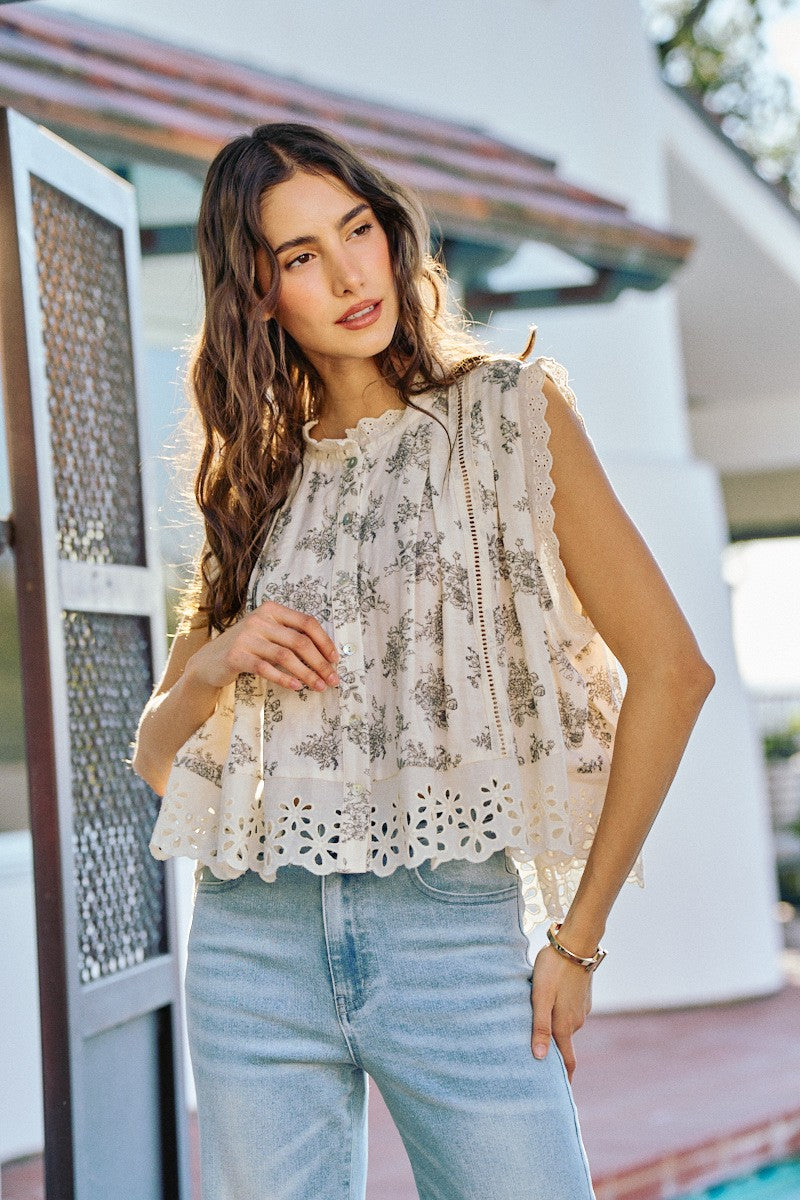 Woman wearing a floral blouse and light blue jeans outdoors.