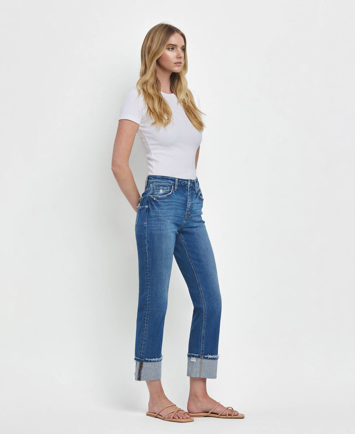 Woman wearing blue jeans and a white top on a light gray background