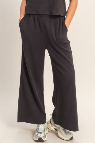 Person wearing black wide-leg pants with a neutral background