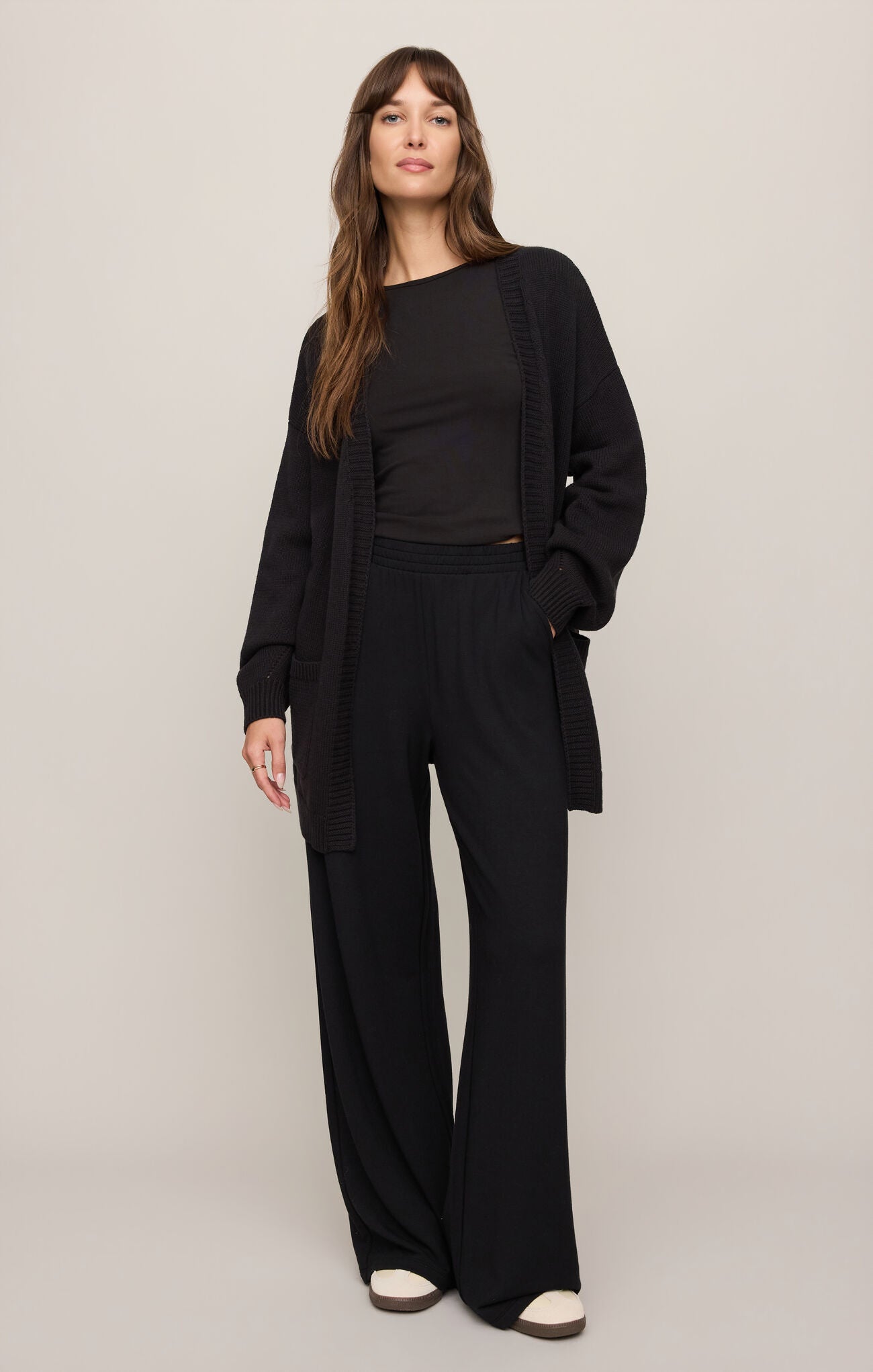 Woman wearing a black outfit with a wide-leg suit on a plain background