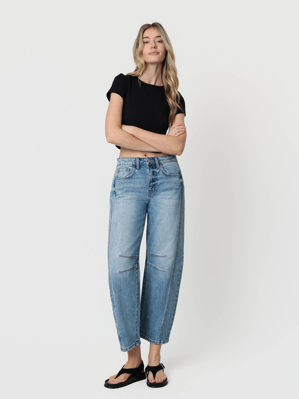 Woman wearing blue jeans and a black top on a white background