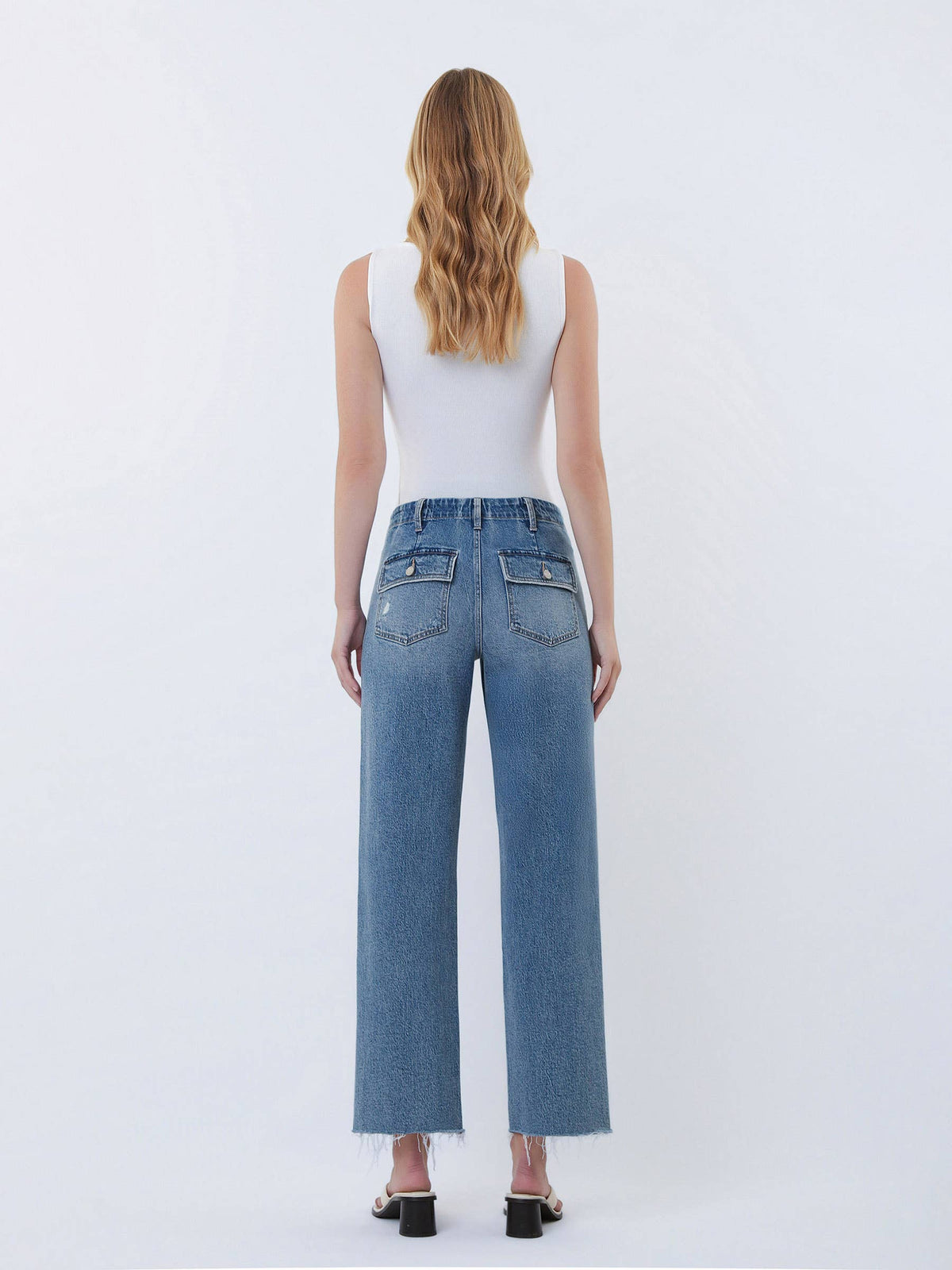 Person wearing blue jeans and a white top on a white background